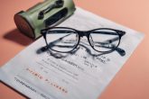 Des lunettes de protection reposant sur une brochure d'information détaillant les soins après une chirurgie oculaire au laser, sur un fond uni.