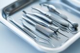 Image haute résolution montrant sept principaux outils dentaires soigneusement disposés sur un plateau en acier inoxydable stérile, sur un fond blanc doux-éclairé pour souligner la propreté et la précision.
